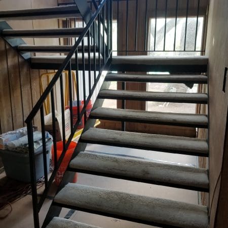 A stairway featuring metal railings alongside a ladder, providing access to an upper level.