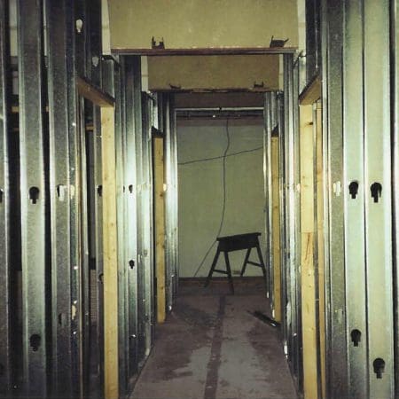 A hallway featuring metal studs along the walls, leading to a closed door at the end.
